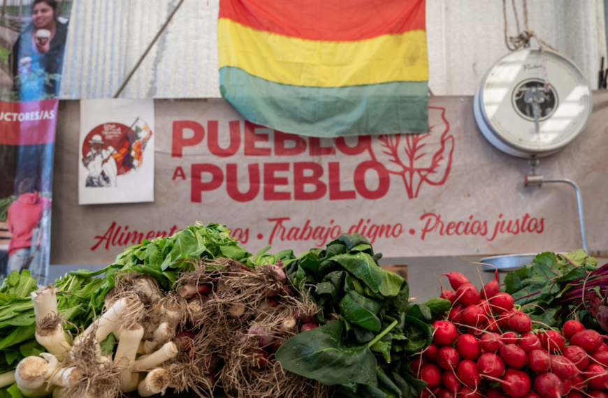Foto de un mercado en Bolivia, con un letrero Pueblo a pueblo que es una red que lleva alimentos agroecologicos a la gente.
