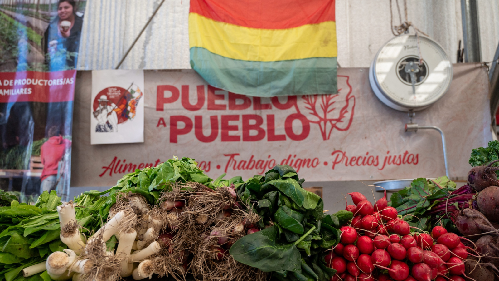 Foto de un mercado en Bolivia, con un letrero Pueblo a pueblo que es una red que lleva alimentos agroecologicos a la gente.